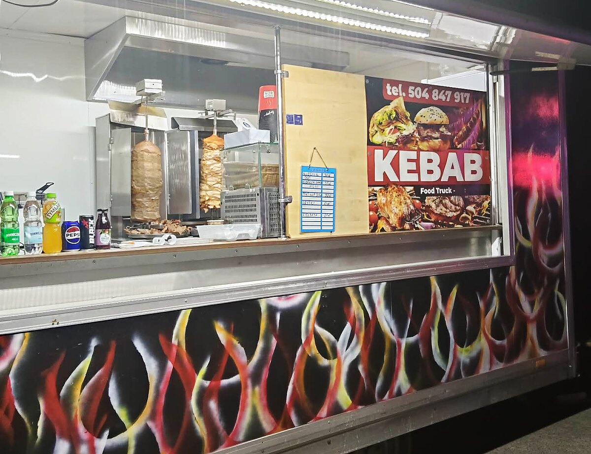 Food truck z kebabem Szewczyk Grill z oświetloną witryną na imprezie wieczorem